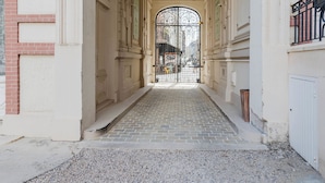 Un pasillo estrecho y pavimentado con una reja decorativa al final.