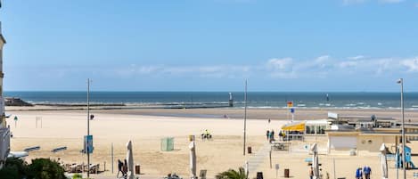 Enjoy the ocean view from our outdoor seating areas, featuring umbrellas and a lifeguard tower nearby.