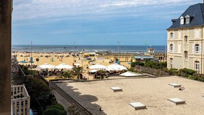 Vista de la playa con un edificio, sombrillas y cielo despejado.