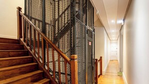 Una escalera de madera con barandilla de metal que lleva a una puerta con mosquitera.