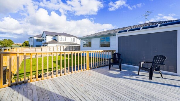 Une terrasse avec deux chaises, une porte de garage et une maison en arrière-plan.