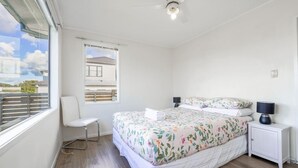 Une chambre à coucher avec un lit, une chaise, une fenêtre et un ventilateur de plafond.
