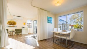 Un salon moderne avec un coin repas, de grandes fenêtres et une vue sur l’extérieur.