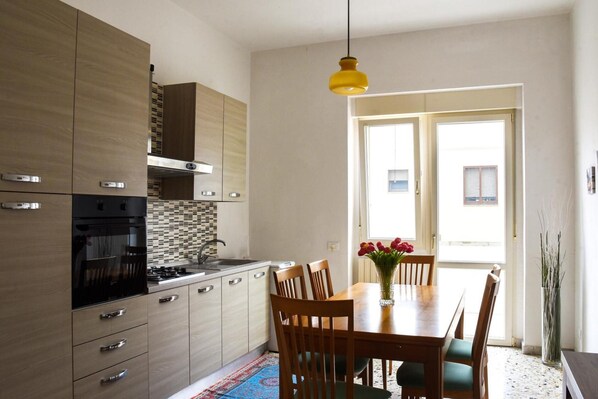 A modern kitchen with wooden cabinets, a gas stove, and a dining table with chairs.