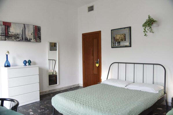 A bedroom with a bed, a dresser, a mirror, and a painting on the wall.