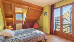Un dormitorio con techo inclinado, una cama, un ventanal y vistas al exterior.