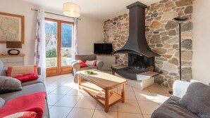 Una sala de estar con una pared de piedra, una chimenea, un televisor y un sofá.