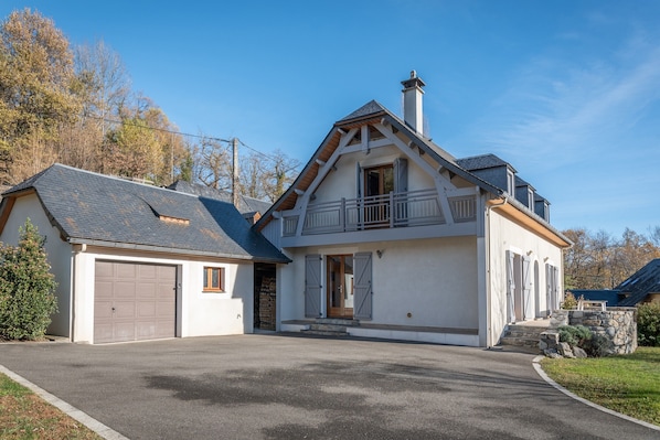 A two-story house with a garage, a balcony, and a stone foundation.