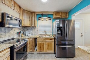A kitchen with wooden cabinets, a stainless steel refrigerator, and a built-in oven.