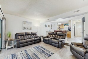 Ein Wohnzimmer mit einer Sofagarnitur, einem kleinen Tisch mit einer Pflanze und einem Teppich.