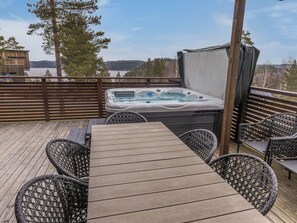 A hot tub on a wooden deck with a view of a lake and trees. - Villa kaarina by Interhome (Lohja)