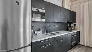 Una cocina moderna con refrigerador de acero inoxidable, gabinetes oscuros, un lavamanos doble y horno empotrado.