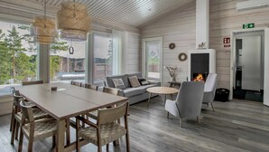 Un interior moderno con comedor, sofá, chimenea y ventanas amplias.