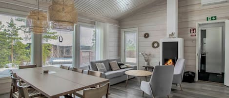 A modern interior with a dining area, sofa, fireplace, and large windows.