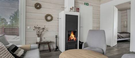 A modern living room with a fireplace, a sofa, a coffee table, and a grey armchair.