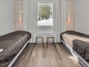 Ein Schlafzimmer mit zwei Betten, einem Fenster mit Jalousien und zwei Wandleuchten.