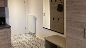 Een moderne badkamer met een grote spiegel, een handdoekrek en een bankje.