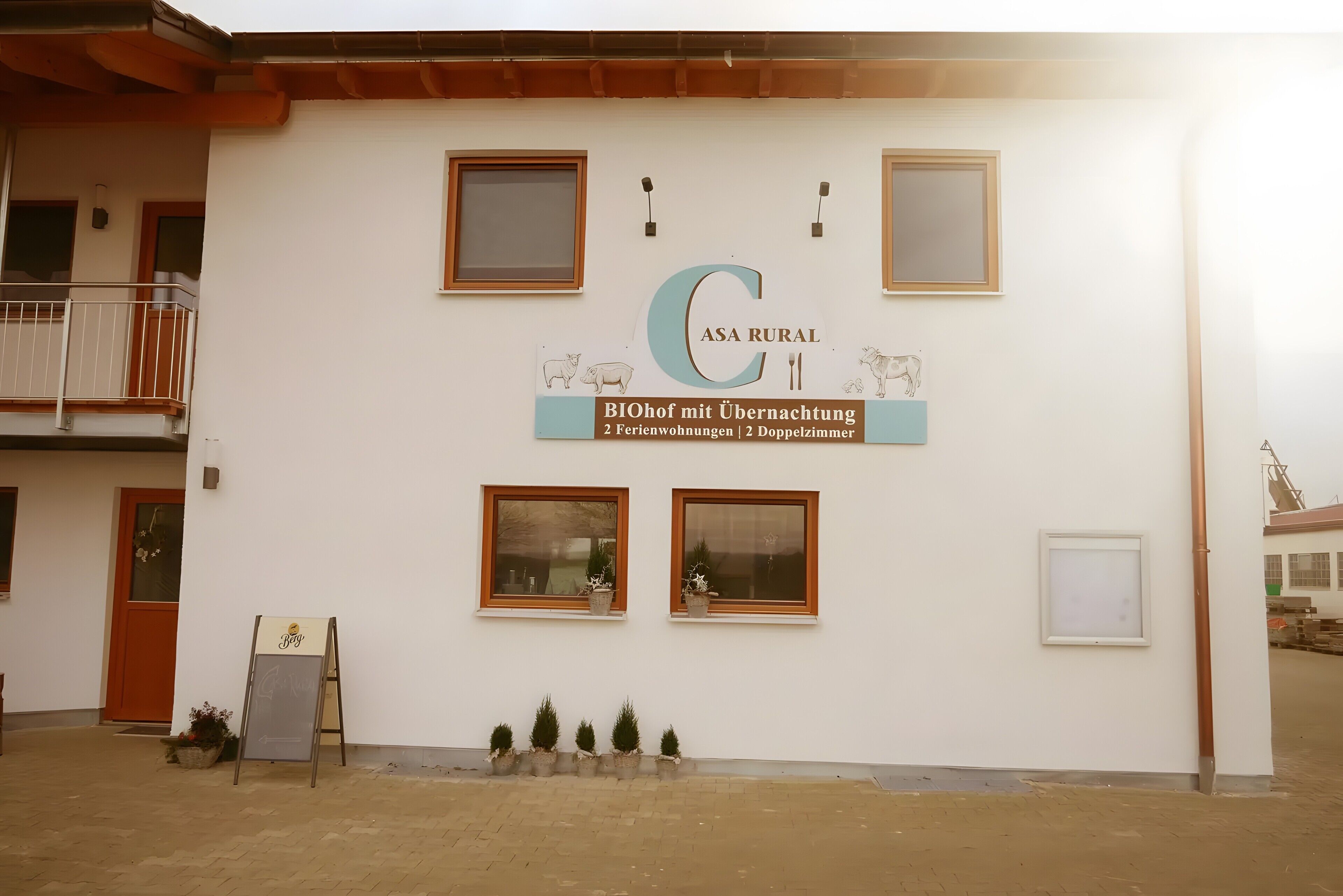 Un bâtiment portant une enseigne indiquant : « ASA RURAL BIOhof mit Übernachtung 2 Ferienwohnungen 2 Doppelzimmer. »