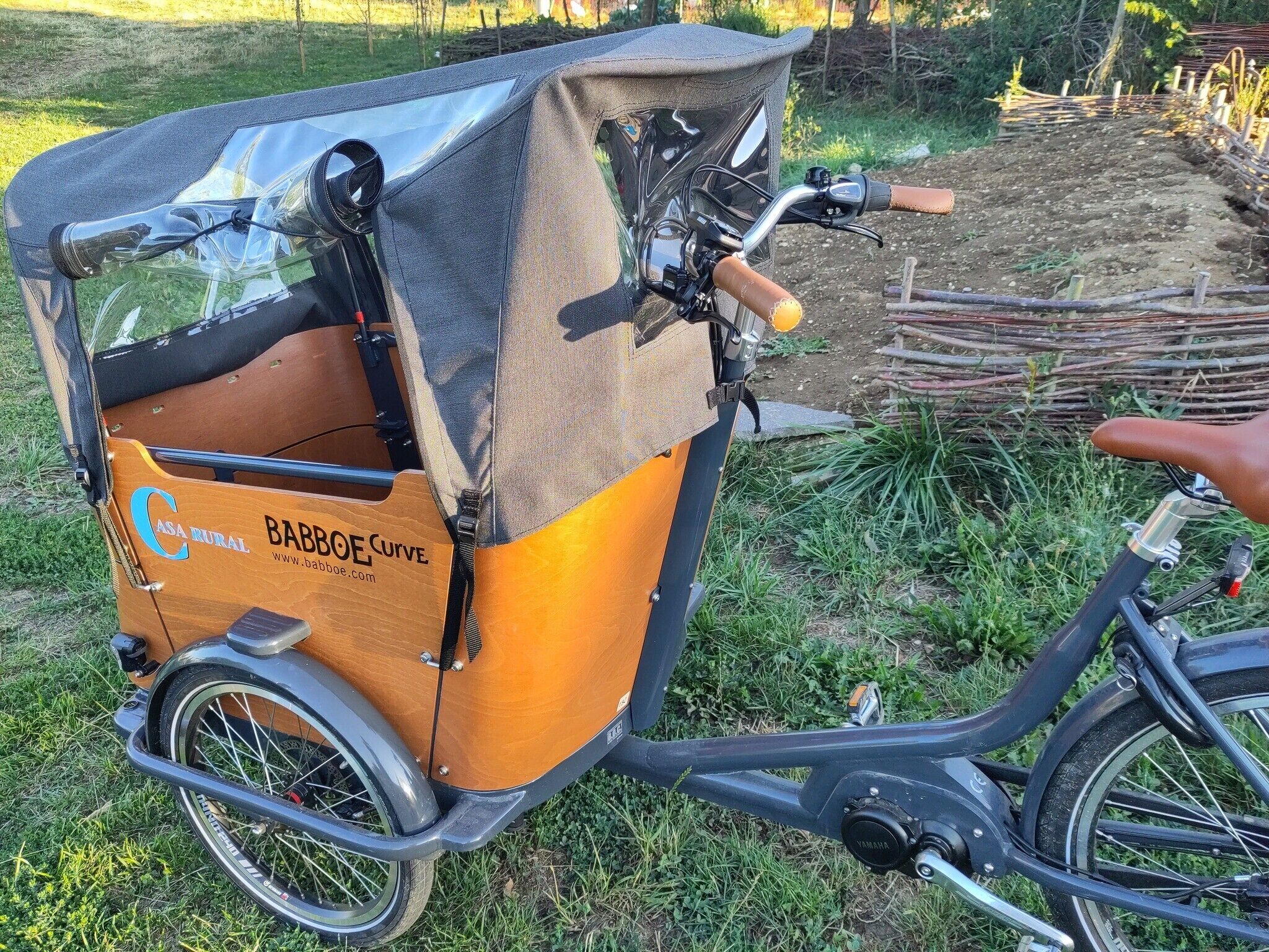 Un vélo équipé d’un coffre de transport portant l’inscription « BABBOE Curve » et indiquant une adresse de site web.