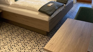 Een moderne slaapkamer met een groot bed, een houten garderobe, een tafel en uitzicht door een glazen deur.