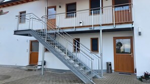 A two-story building with a metal staircase, wooden doors, and a balcony. - Apartment '2' with Shared Terrace, Shared Garden and Wi-Fi (Nerenstetten)
