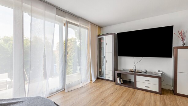 A bedroom with a bed, a desk, a TV, and a wardrobe.