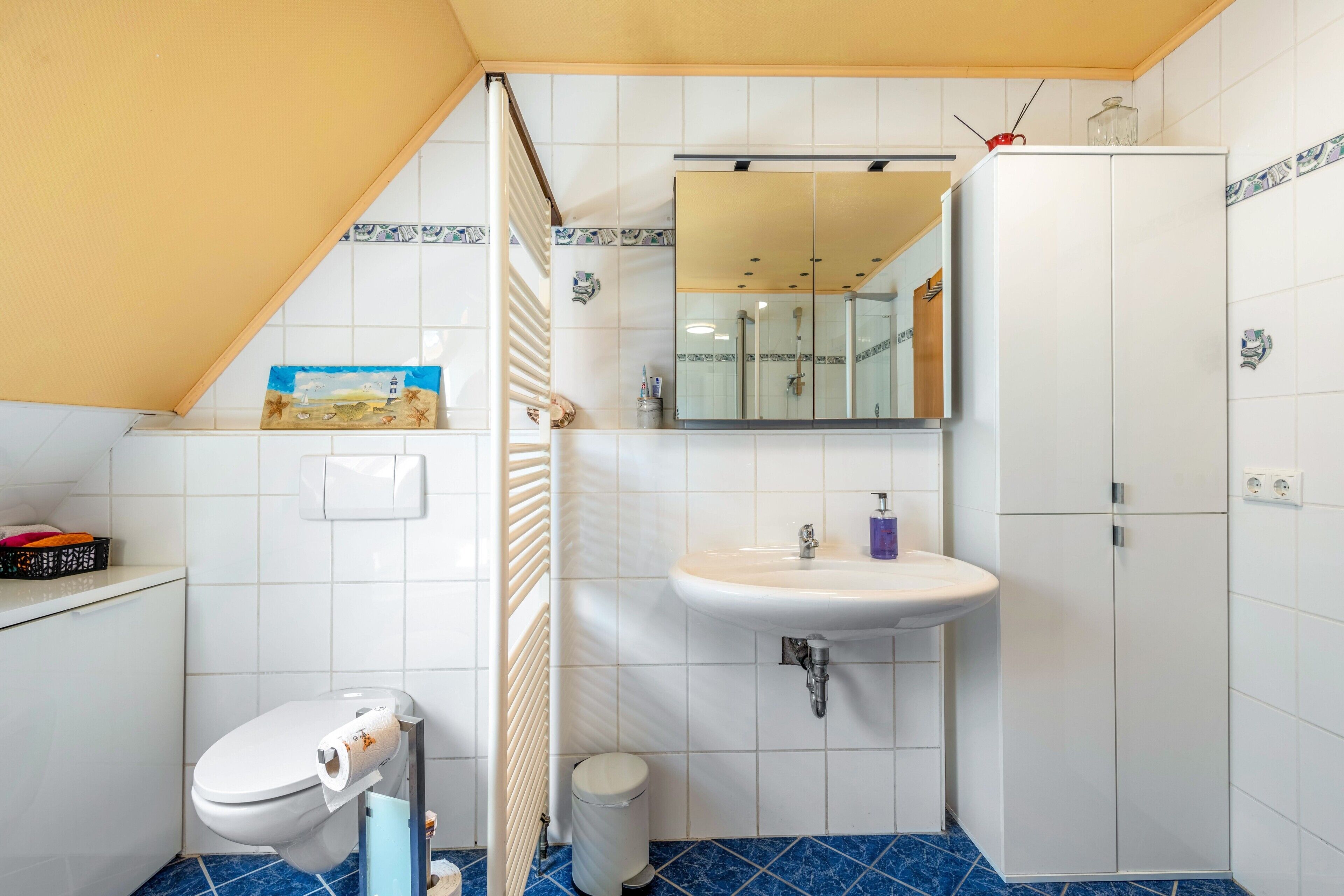 Une salle de bain comprenant des toilettes, un lavabo, un miroir et des placards.