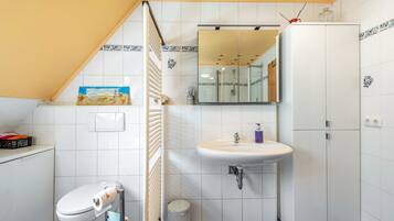 Une salle de bain comprenant des toilettes, un lavabo, un miroir et des placards.