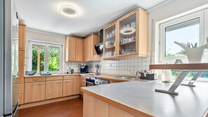 A modern kitchen with wooden cabinets, a large island, and a window providing natural light.