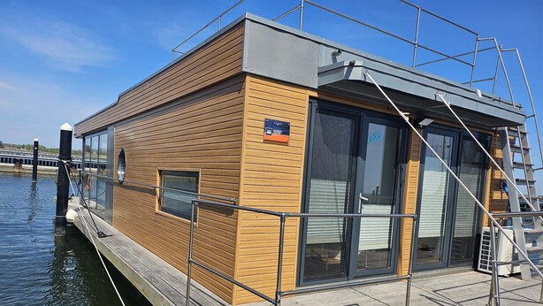 Um barco moderno com revestimento de madeira, porta de vidro e corrimão de metal.