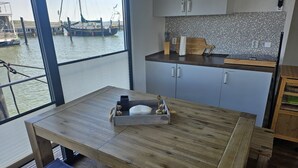 Uma cozinha moderna com uma grande janela com vista para uma marina, mobiliário de madeira e painel de azulejos.