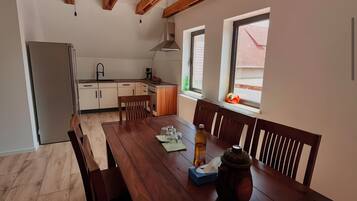 Een moderne keuken met houten balken, een eettafel met stoelen en een koelkast.