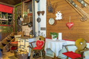 A rustic interior with wooden walls, a vintage stove, and various decorative items including heart-shaped ornaments and a wooden chair.