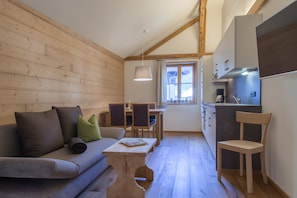 A cozy cabin interior with a wooden interior, a sofa, a dining table, and a kitchen area.