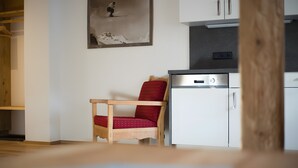 Una habitación con una silla de madera, un mueble blanco pequeño y un cuadro en la pared.