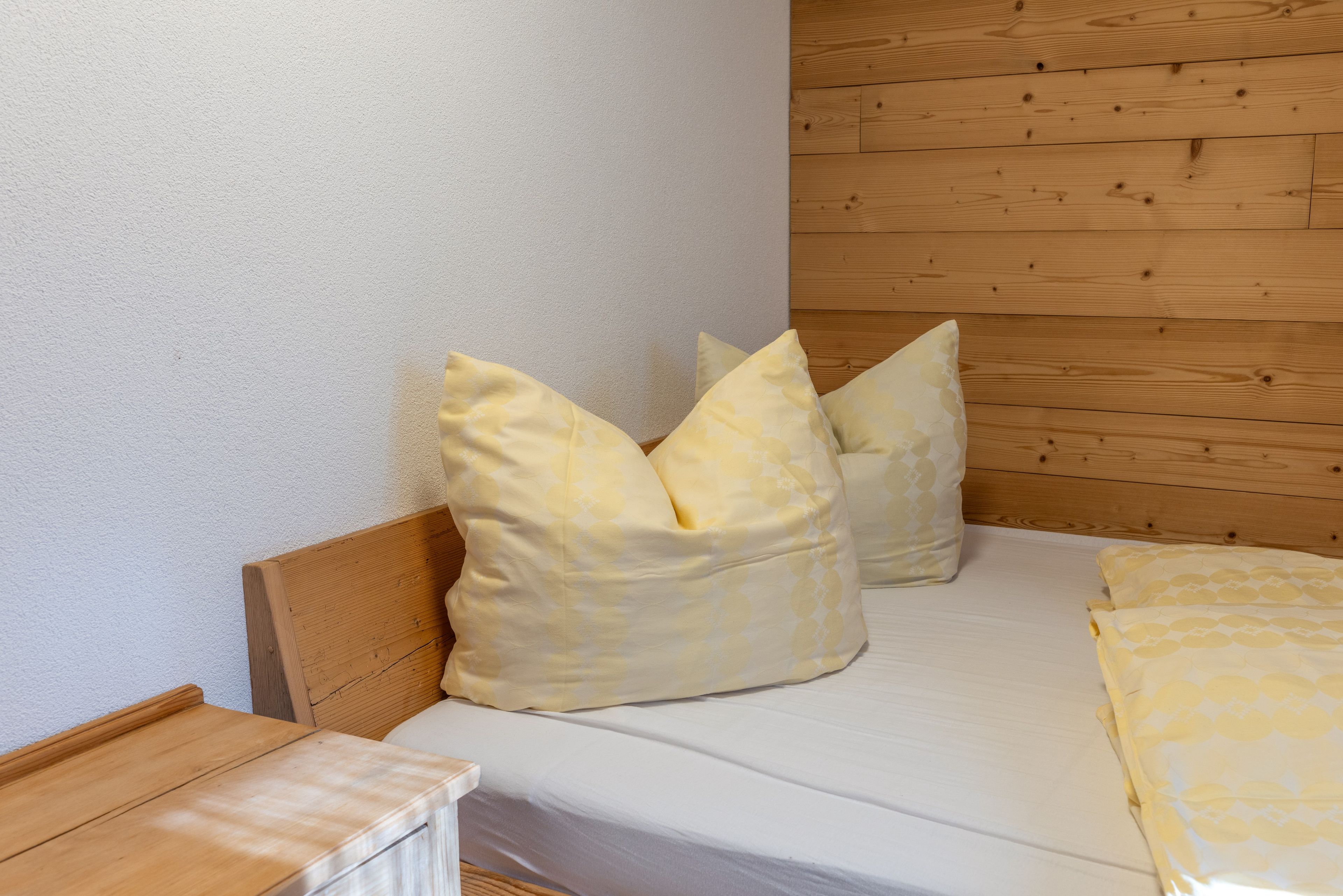 A bed with a wooden headboard, two pillows, and a white mattress.