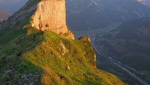 A mountainous landscape with a prominent rock formation and a valley below.