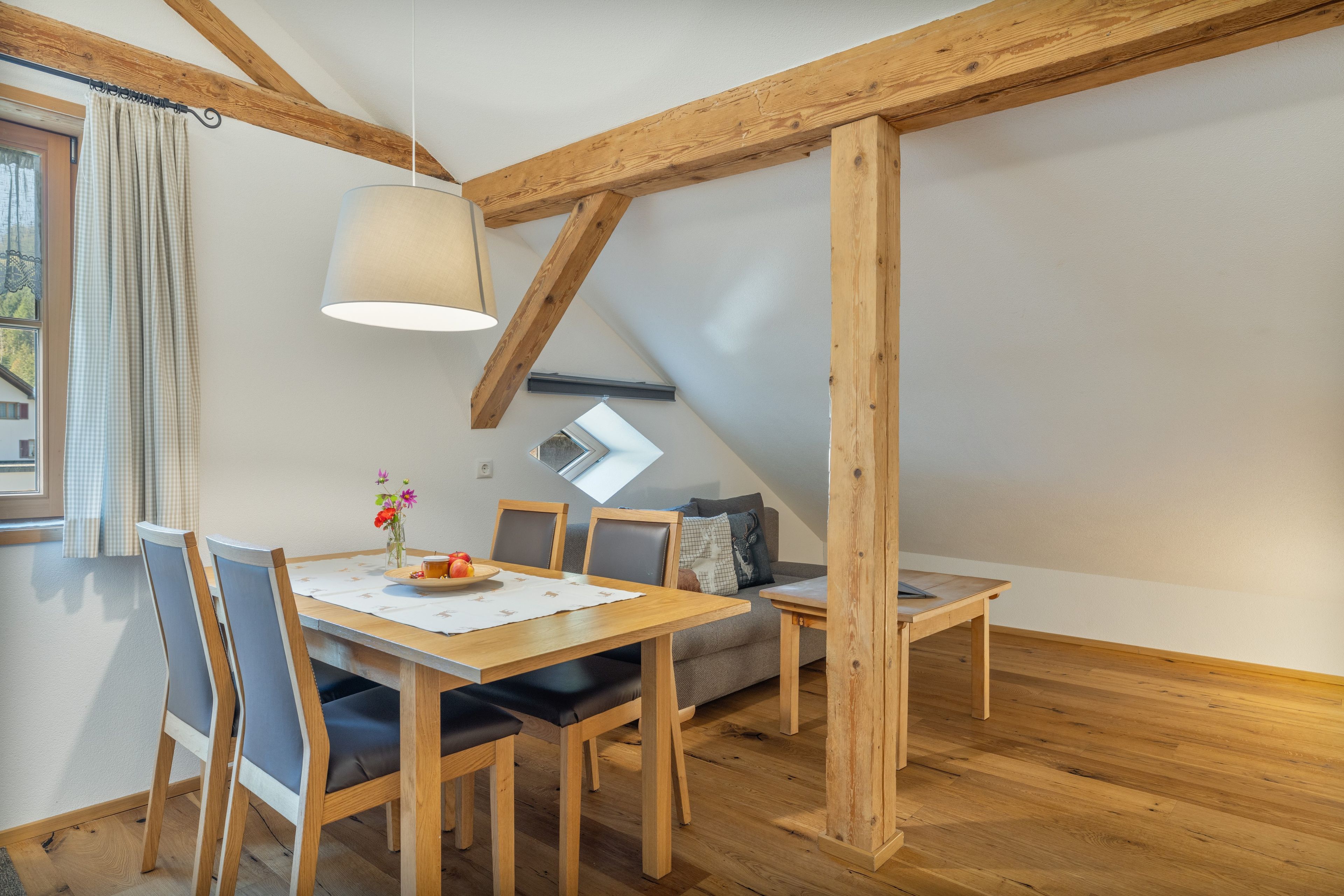 Un comedor con una mesa de madera, sillas y una lámpara colgante.