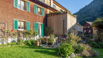 Un chalet traditionnel avec une façade en briques, des volets verts et une extension en bois.