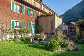 A traditional chalet with a brick facade, green shutters, and a wooden extension.