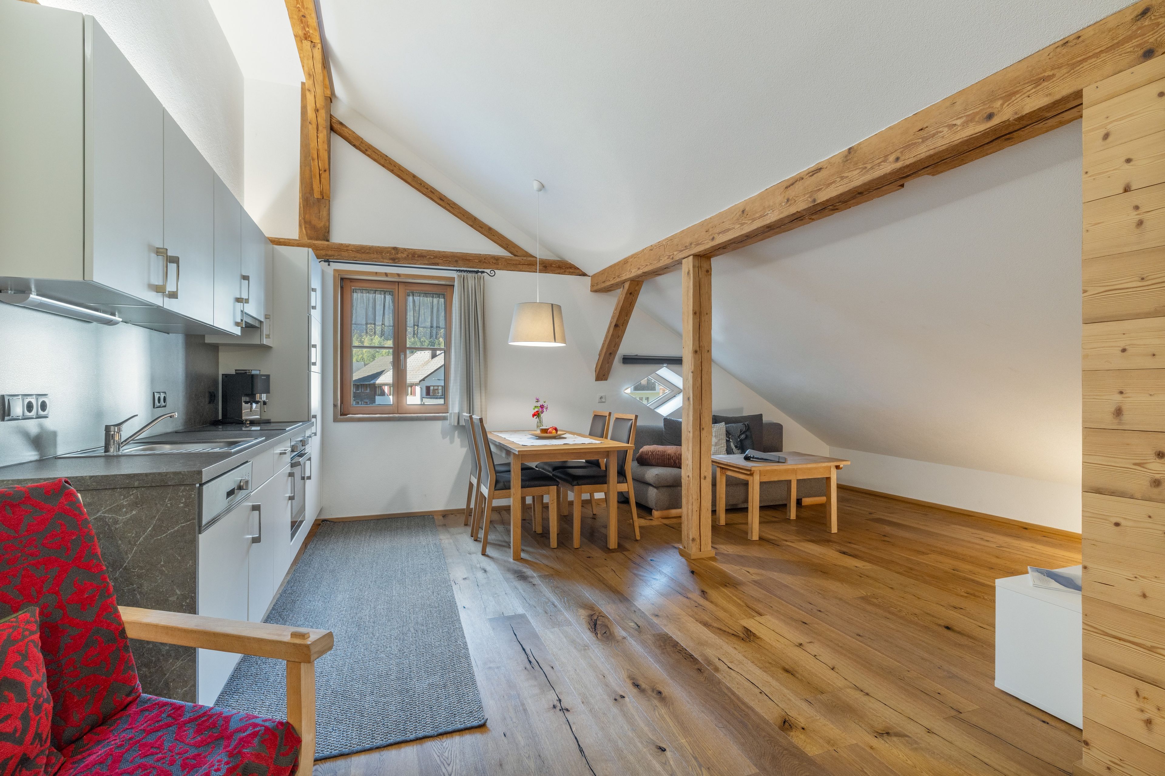 Eine kompakte Küche mit modernen Geräten, ein Essbereich mit Tisch und Stühlen und eine gemütliche Sitzecke mit einer Couch.