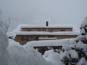 A two-story building with a snow-covered roof and a chimney.