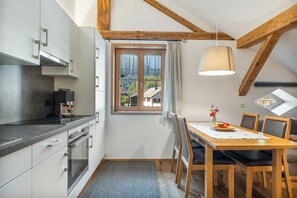 A compact kitchen with modern appliances, a dining area with a table and chairs, and a window with a view of a house.