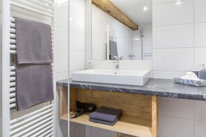 A modern bathroom with a white sink, a mirror, and a towel rack.