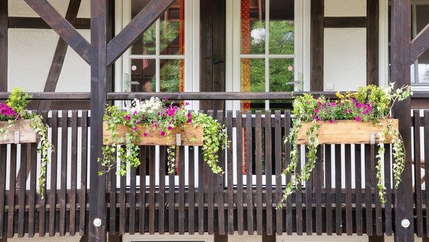 A wooden balcony with vertical slats and flower planters. - Apartment 'Stallblick' with Shared Terrace, Shared Garden and Wi-Fi (Bad Urach)