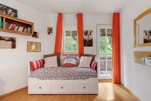 A bedroom with a bed, a bookshelf, a window, and curtains. - Apartment 'Stallblick' with Shared Terrace, Shared Garden and Wi-Fi (Bad Urach)