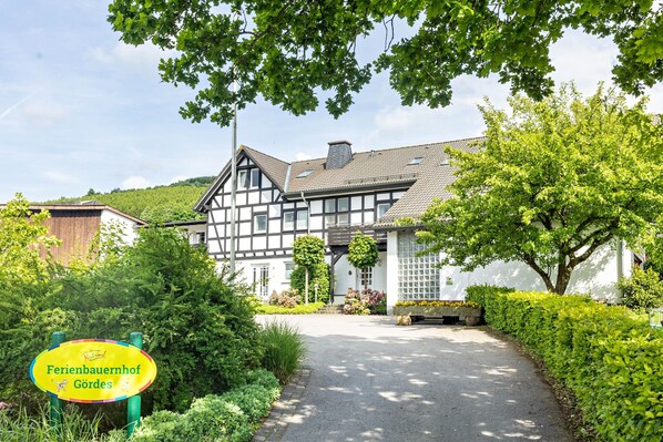 A traditional half-timbered house with a paved driveway and lush greenery.