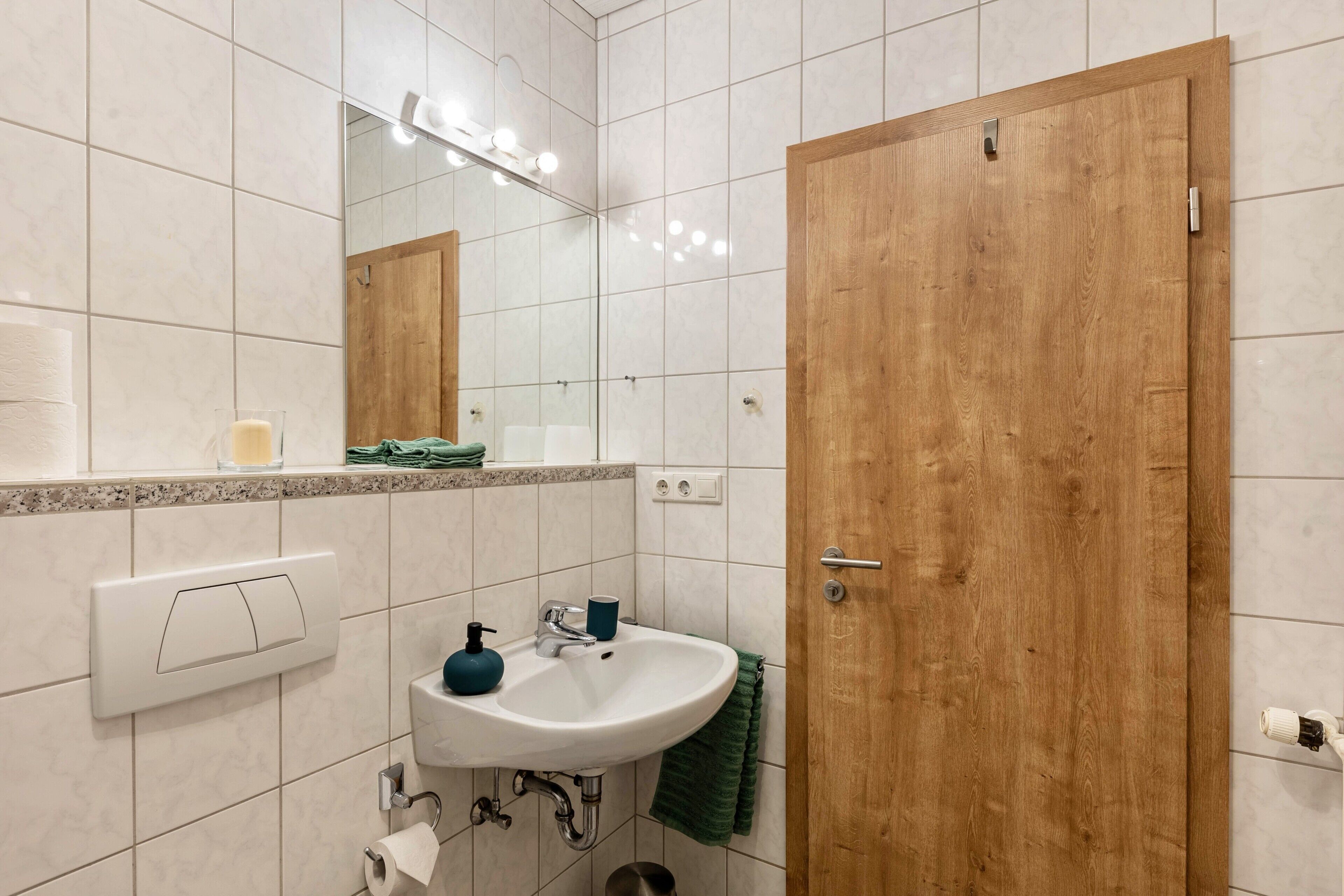 Une salle de bain avec un lavabo, un miroir et une porte en bois.