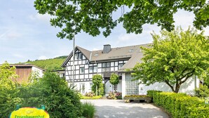 A traditional half-timbered house with a paved driveway and lush greenery. - Apartment (Fuchsbau, 30 sqm) with Private Terrace and Wi-Fi (Schmallenberg)