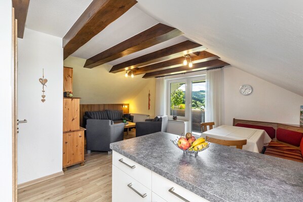 Une cuisine dotée d’un plan de travail en granit, de meubles en bois et d’un coin repas avec une table et des chaises.
